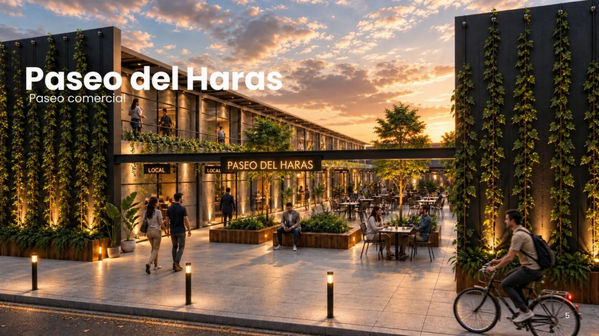 Paseo del Haras al atardecer visto desde la calle, con vidrieras iluminadas en dos plantas, letrero 'PASEO DEL HARAS' central, muros verdes de enredadera y peatonal con cantero central